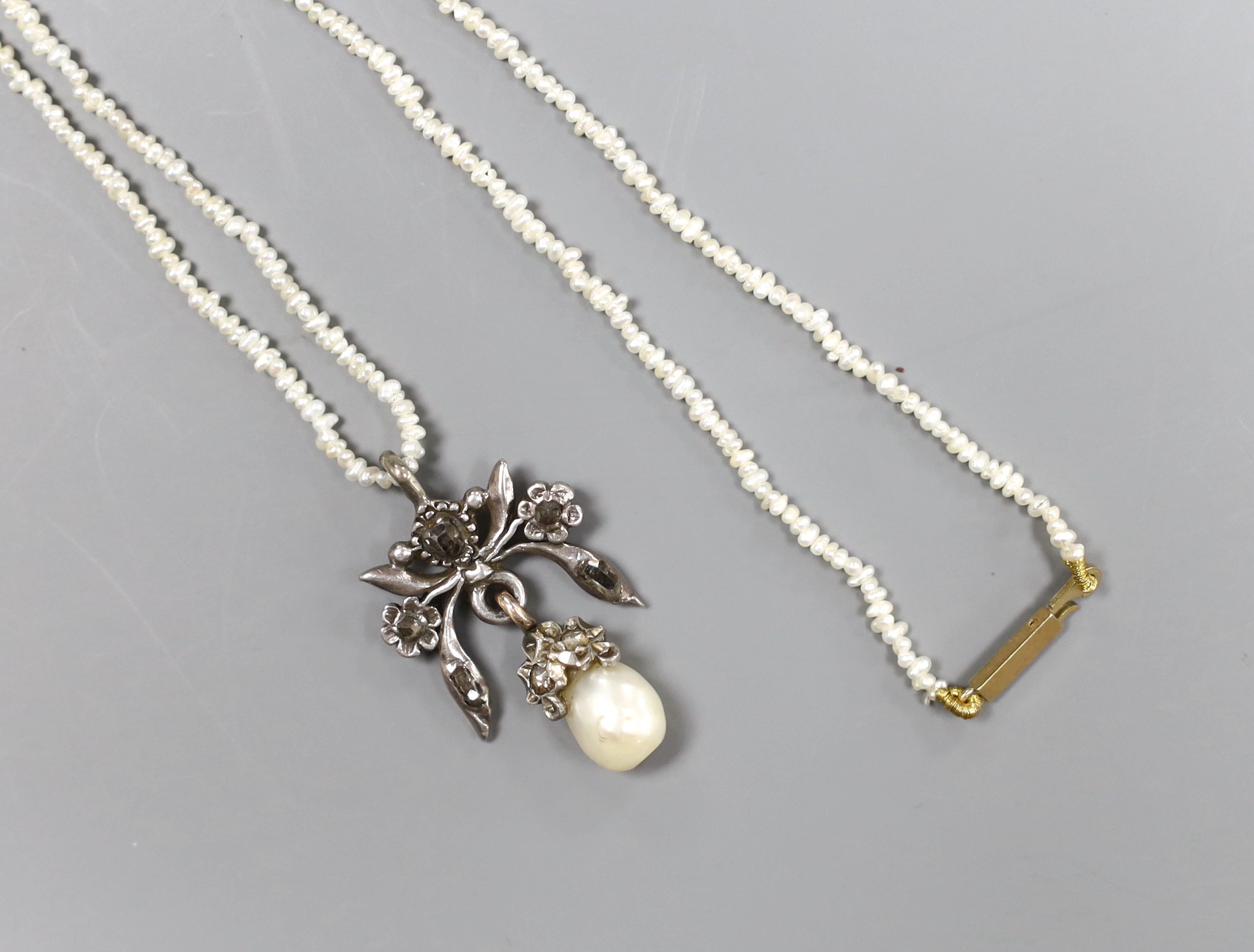 An Indian rose diamond and baroque pearl white metal mounted drop pendant, on a seed pearl necklace